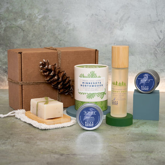 Room Spray, Candle, Shower Lotion bar, Legacy Soap and Slather lotion bar on hard surface next to gift box.