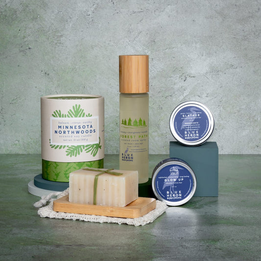 Room Spray, candle, lotion bar, legacy soap and shower lotion bar on hard surface with neutral background.