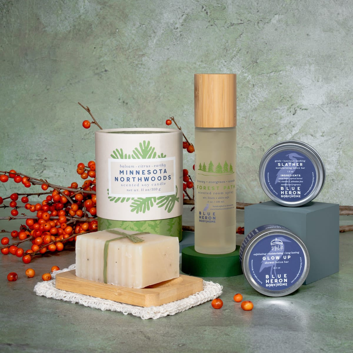 Candle,  room spray lotion bar, shower lotion bar and accessories on hard surface with berries.